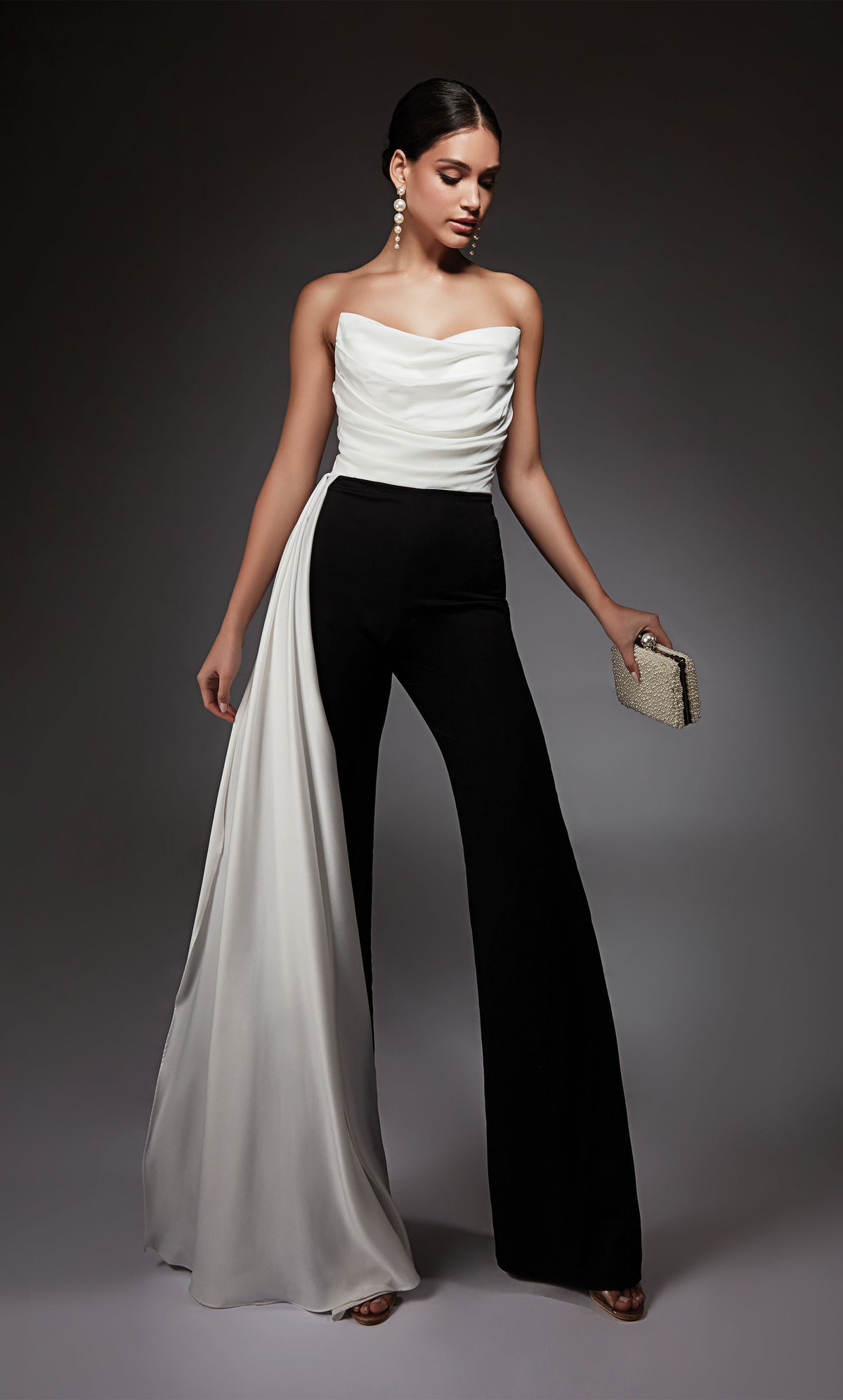 A chic, strapless jumpsuit with a white ruched top and cascading drape, and black wide leg pant.