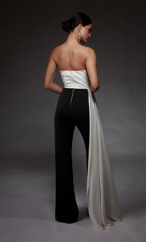 A chic, strapless jumpsuit with a white ruched top and cascading drape, and black wide leg pant.