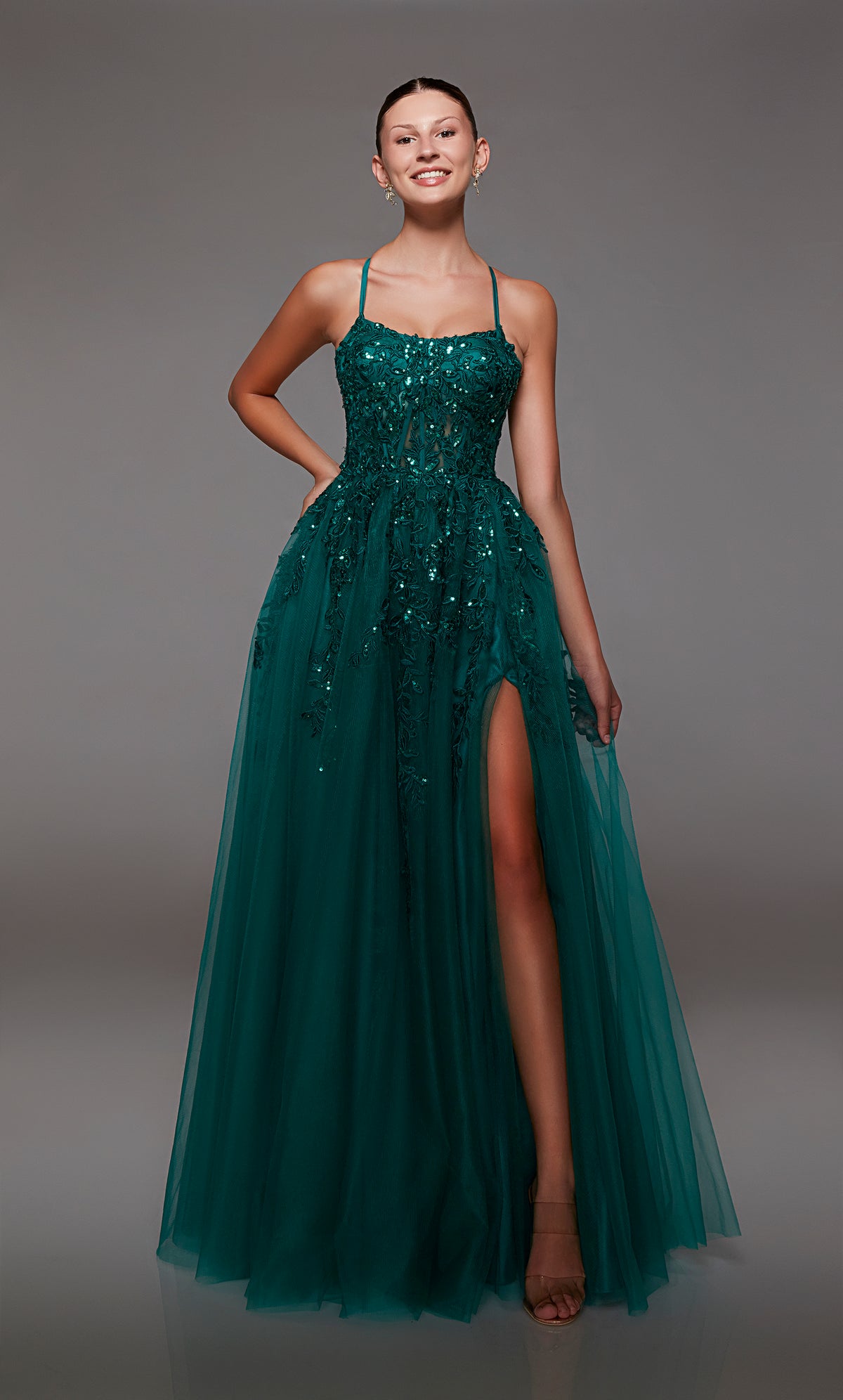 Green prom dress: sheer corset bodice, full tulle skirt with front slit, lace-up back, and intricate floral lace appliques for an enchanting look.