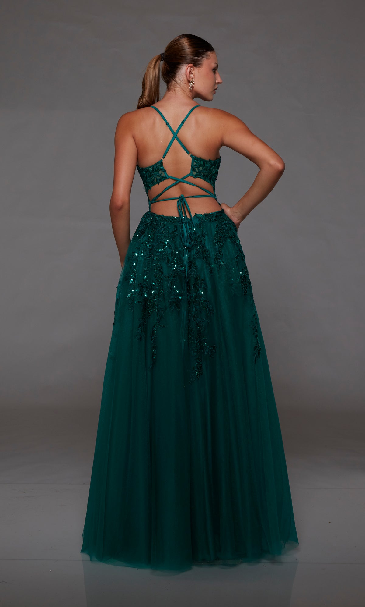 Green prom dress: sheer corset bodice, full tulle skirt with front slit, lace-up back, and intricate floral lace appliques for an enchanting look.