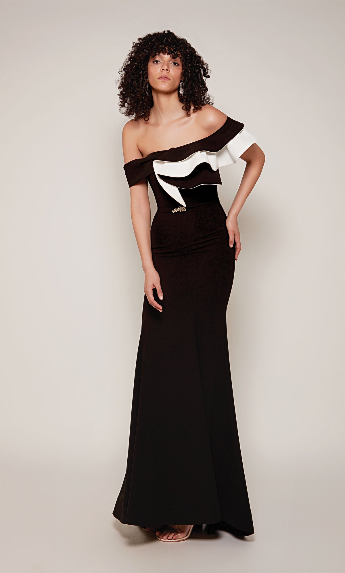 A black and white evening gown with an off-the-shoulder neckline and ruffle bodice. In addition, the dress has a faux belt at the waistline and a slight train.