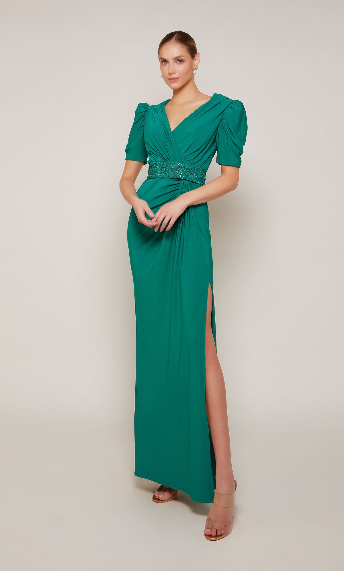 An emerald evening gown with puff sleeves, a V-neckline, an embellished belt, and elegant side slit.