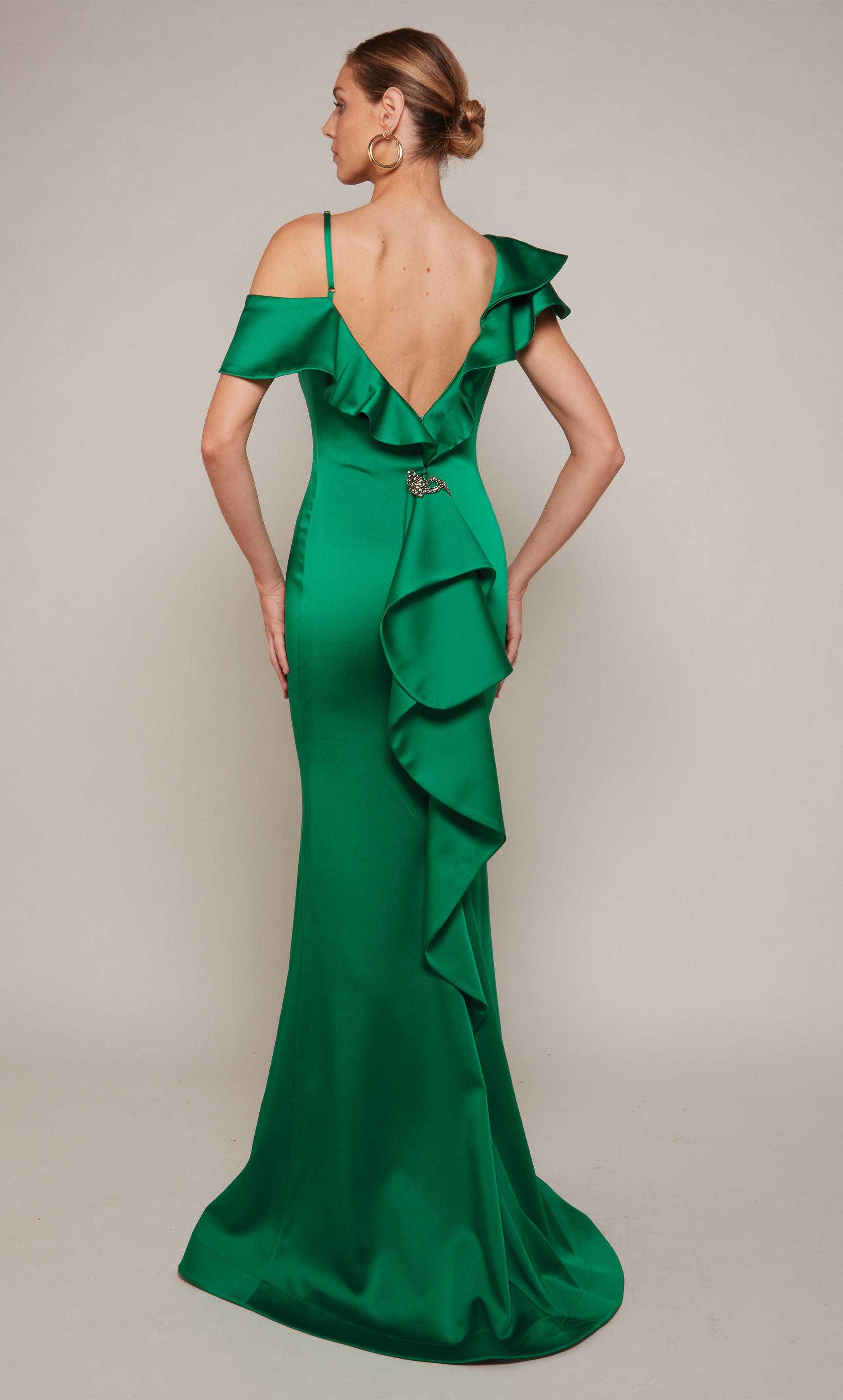 A satin formal dress featuring a one shoulder neckline, a fitted silhouette, and ruffles in emerald green.