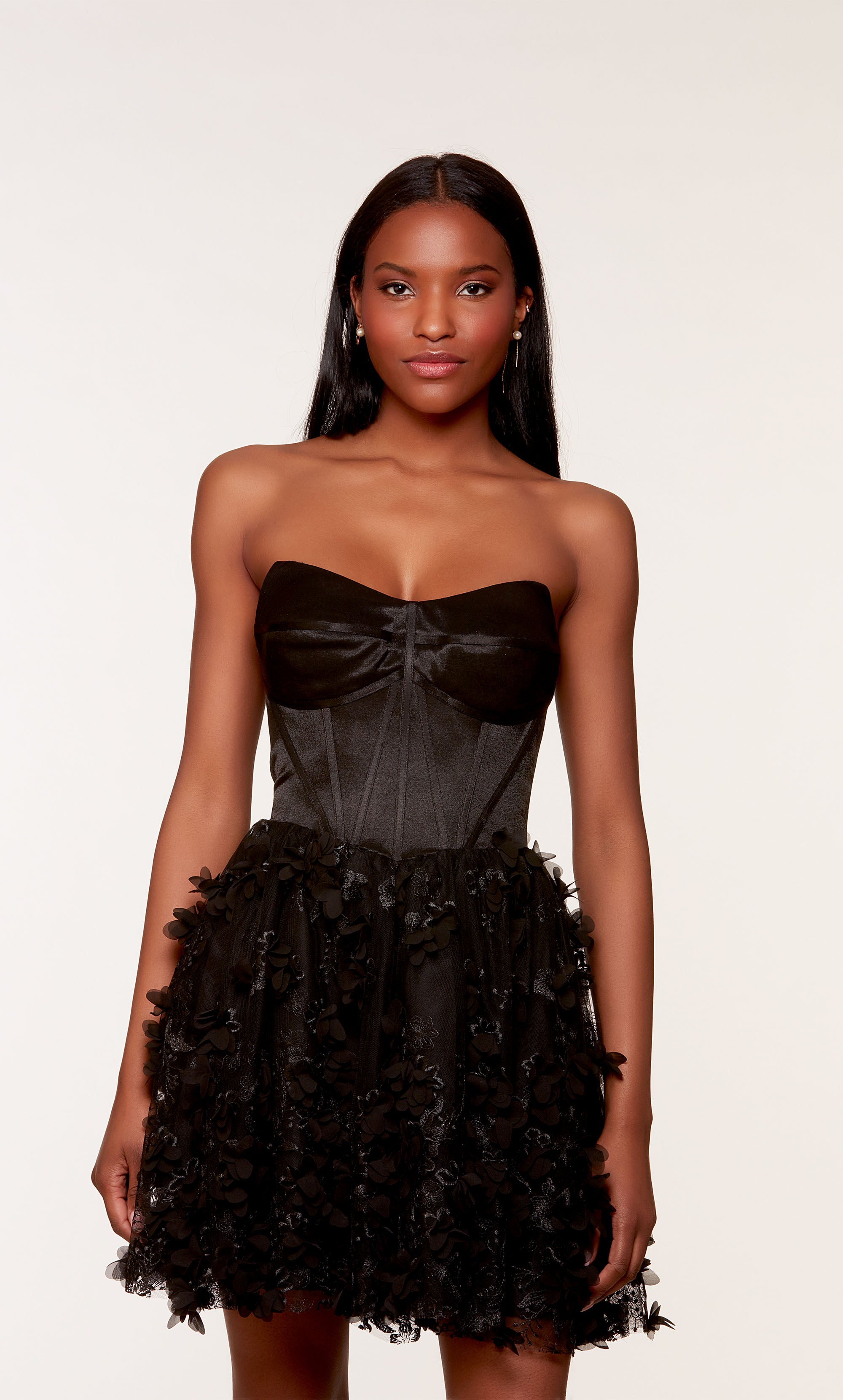 A black strapless satin corset dress, showcasing a fitted bodice and a flared skirt adorned with intricte 3D flowers.