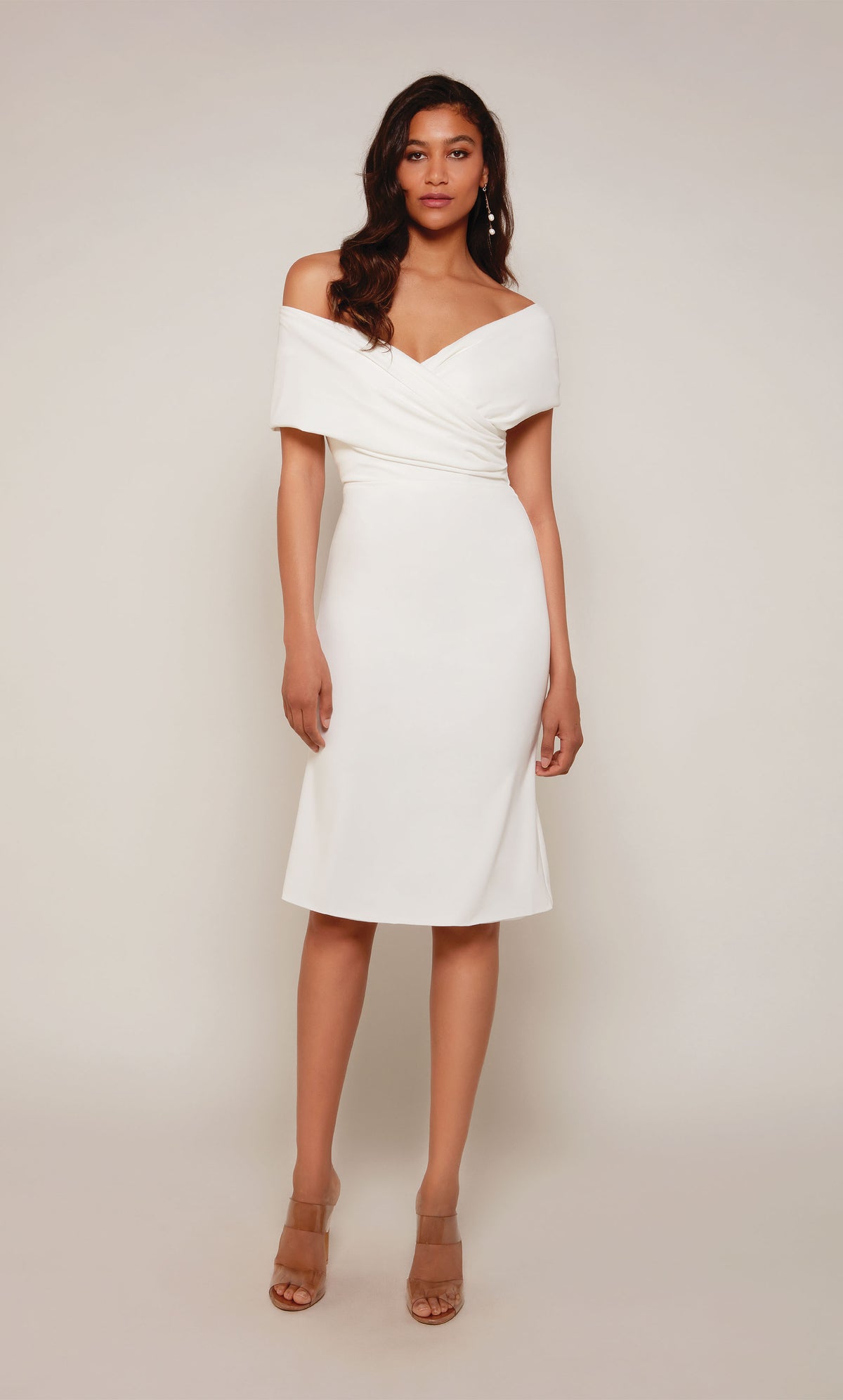 A chic, knee length cocktail dress with an off the shoulder neckline, ruching detail, and a closed zipper back in ivory.