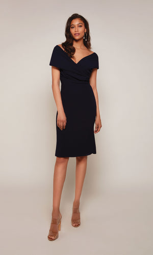 A chic, knee length cocktail dress with an off the shoulder neckline, ruching detail, and a closed zipper back in midnight blue.