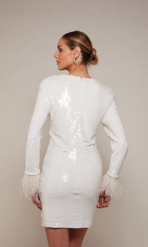 A short, long sleeve cocktail dress with feather trimmed sleeves and a closed zipper back in ivory sequins.