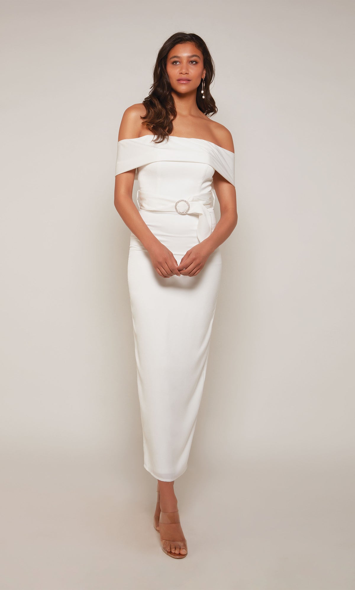 A  white, satin midi dress with an off the shoulder neckline and thick belt at the waistline. The skirt is a fitted pencil skirt with a back slit.