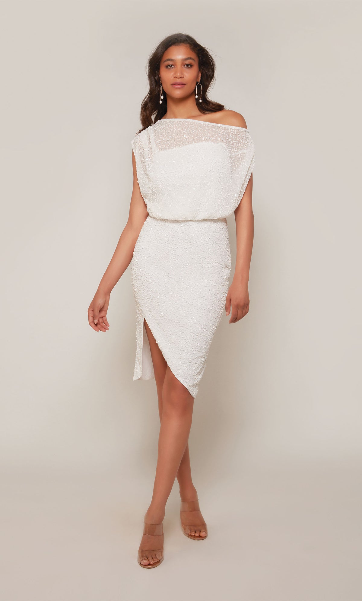 A shimmery, hand beaded, ivory cocktail dress with a one shoulder neckline, a cinched waist, and an asymmetrical hemline.