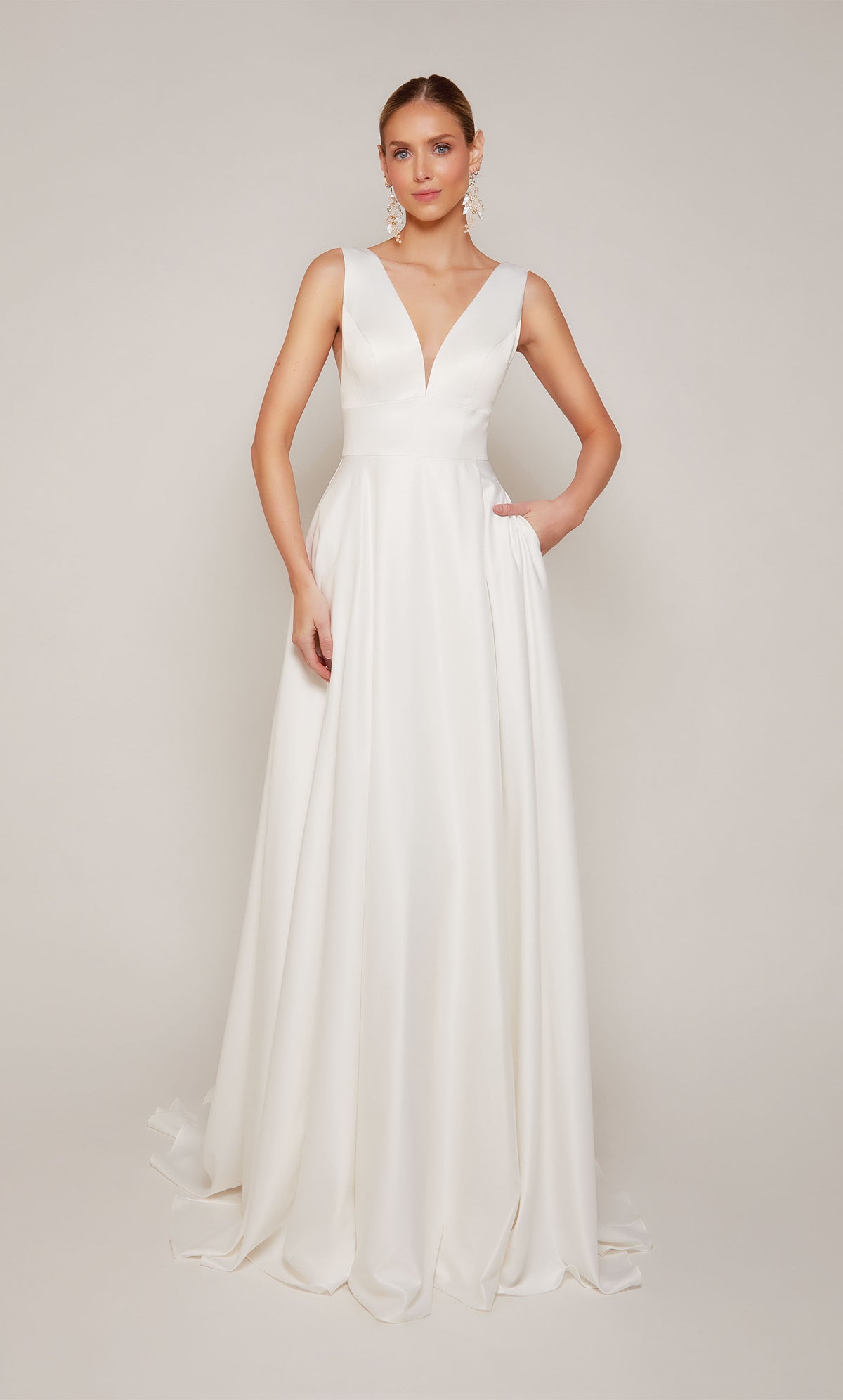 Simple satin A-line wedding dress in diamond white with a plunging neckline, open back, and satin covered buttons on the elegant train.